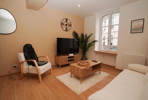 a living room with a tv and a chair and a table at La Bulle Chic, Netflix - central in Montargis