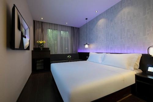 a bedroom with a large white bed with a purple wall at Jinglai Hotel Changshou Road Subway Station Branch in Shanghai