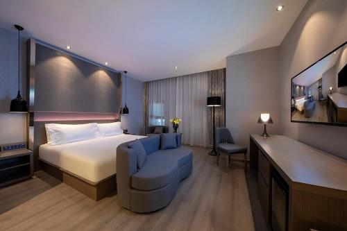 a hotel room with a bed and a blue chair at Jinglai Hotel Changshou Road Subway Station Branch in Shanghai