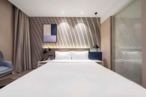 a bedroom with a large white bed and a couch at Jinglai Hotel Changshou Road Subway Station Branch in Shanghai