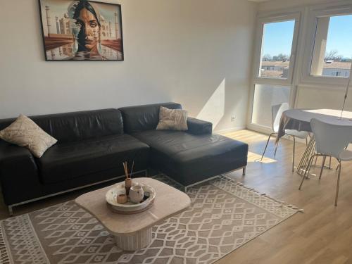 un salon avec un canapé noir et une table dans l'établissement Appartement festival avignon, à Avignon