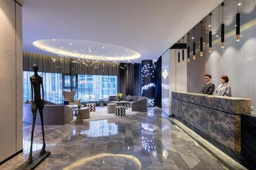 a lobby with a man and a woman standing at a counter at Jinglai Hotel Changshou Road Subway Station Branch in Shanghai