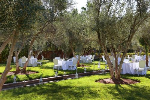 a garden with white tables and chairs under trees at Le Bled Ferme in Marrakech