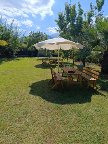 a picnic table with an umbrella and two benches at Dimis apartments in Leptokaria