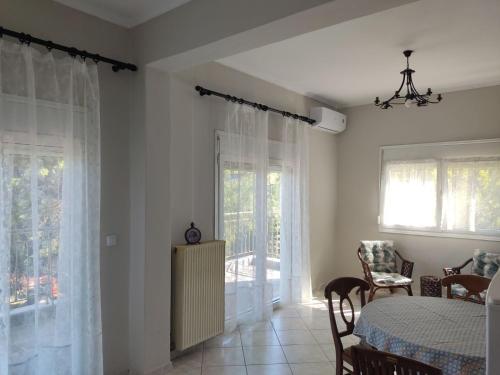 a dining room with a table and some windows at Country treasure in Nea Michaniona