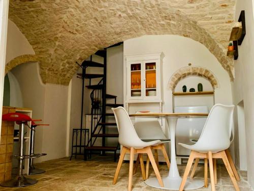een eetkamer met een tafel en witte stoelen bij Casa L'Isule in Cisternino