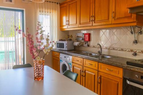 a kitchen with wooden cabinets and a vase of flowers on a counter at Moradia Valdemar in Nazaré