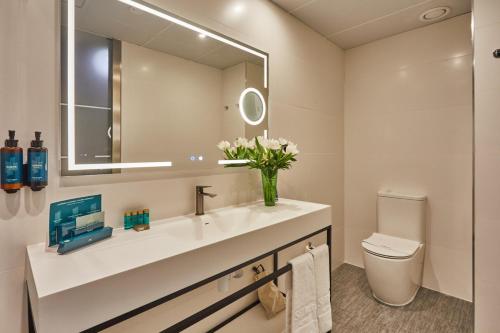 a bathroom with a sink and a mirror and a toilet at Silken Puerta Valencia in Valencia