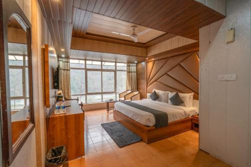 une chambre avec un grand lit et une grande fenêtre dans l'établissement The Dynasty Resort, à Nainital