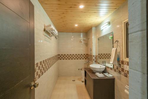 une salle de bain avec un lavabo et un miroir dans l'établissement The Dynasty Resort, à Nainital