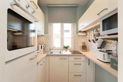a kitchen with white cabinets and a sink and a window at Ferienhaus Brasch in Grömitz