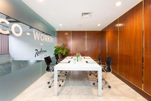 a conference room with a white table and black chairs at Radisson Suites Bangkok Sukhumvit in Bangkok