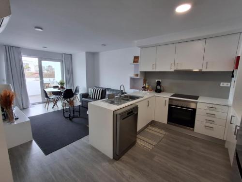 a kitchen with white cabinets and a living room at Smile and Wave Apartment in Ponta Delgada