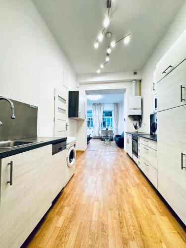 a large kitchen with wooden floors and white cabinets at Lovely 2BR for 5P Peaceful & Central Stay in Klosterneuburg