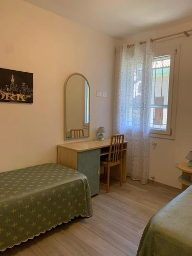 a bedroom with a bed and a desk and a mirror at Appartamento Oberdan in Milano Marittima