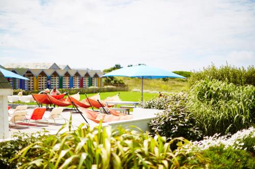 eine Gruppe von Stühlen, Tischen und einem Schirm in der Unterkunft St Moritz Hotel Houses in Polzeath