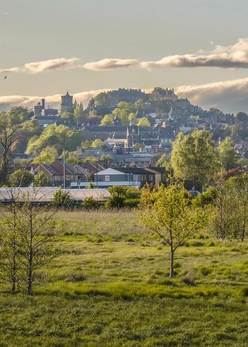 a view of a city from a field with trees at Castle View - Home from Home in Stirling