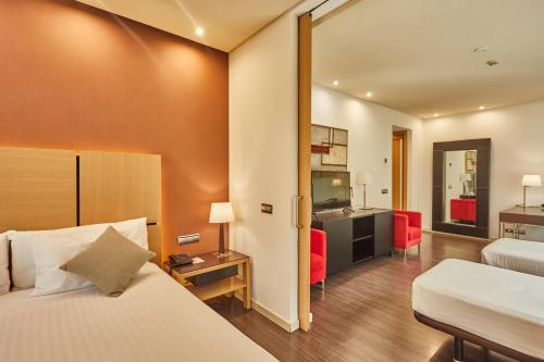 a hotel room with a bed and a living room at Silken Puerta Valencia in Valencia