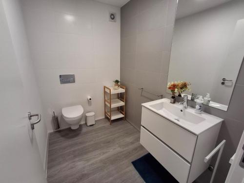 a white bathroom with a sink and a toilet at Smile and Wave Apartment in Ponta Delgada