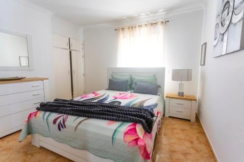 a white bedroom with a bed and a dresser at Moradia Valdemar in Nazaré