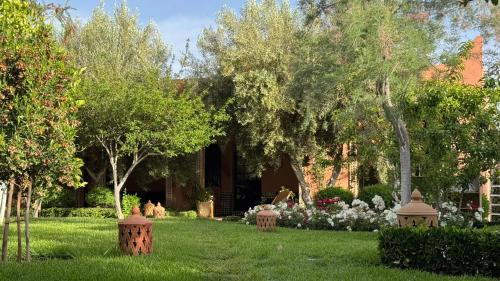 a garden with trees and flowers in front of a house at Dar Tidyan - Maison d'hôtes in Igzi Ou Fella