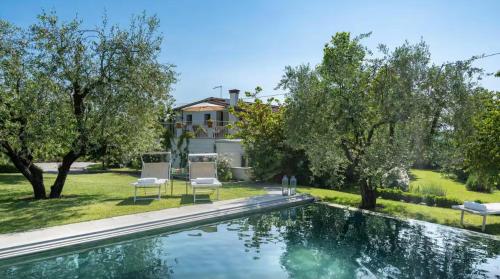 a swimming pool with two chairs and a house at Villa La Memma - Private Villa with Pool for 6 in Case Malva