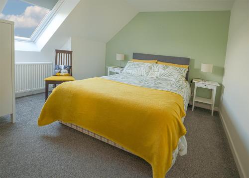 a bedroom with a large bed with a yellow blanket at Castle View - Home from Home in Stirling