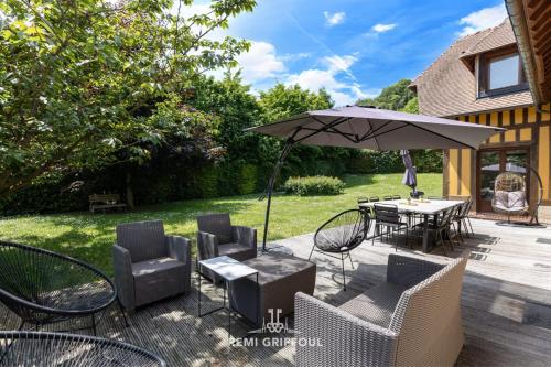 un patio avec une table, des chaises et un parasol dans l'établissement Eva Home - Magnificent villa with Garden - Honfleur 10 Pax, à Honfleur