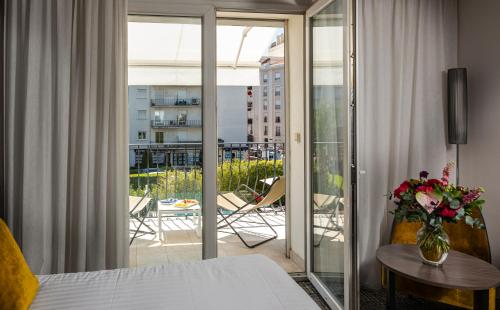 Cette chambre dispose d'un lit et d'une porte en verre avec un balcon. dans l'établissement Hôtel Le Canberra, à Cannes