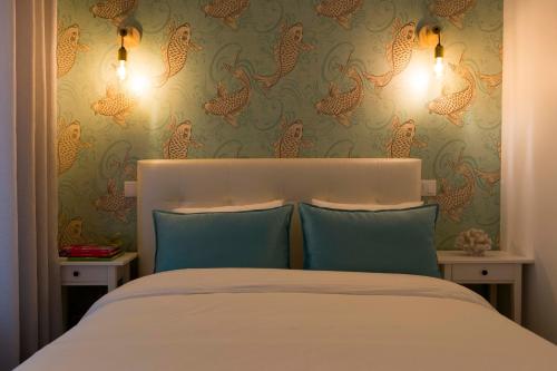 a bedroom with a bed with blue pillows and wallpapers at Home Sweet Praia in Nazaré