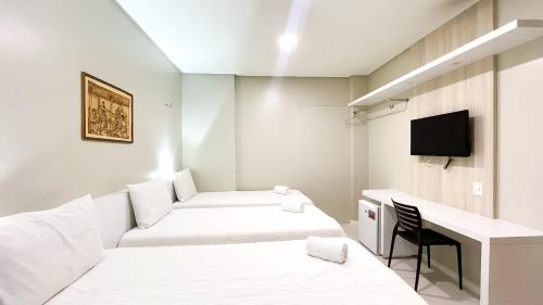 a small room with two beds and a desk at Hotel Padre Cícero in Juazeiro do Norte