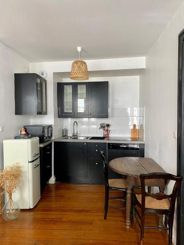 La cuisine est équipée de placards noirs, d'une table et d'un réfrigérateur. dans l'établissement Saint Etienne - Agréable T2 quartier Cathédrale, à Strasbourg