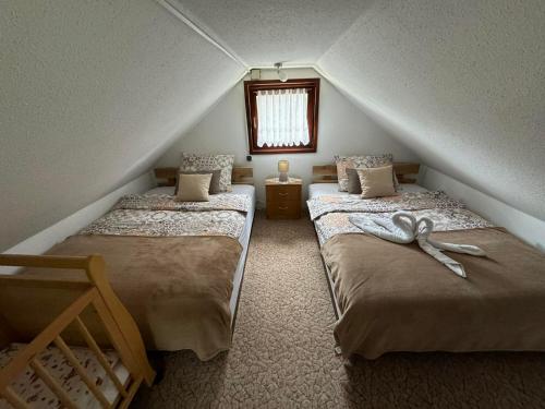 a attic room with two beds and a window at Holiday Home Manda in Tounj
