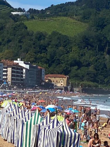 a crowd of people on a beach with umbrellas at Etxeberria in Zarautz