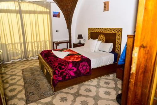 a bedroom with a large bed with a purple blanket at Flamingo Memnon Guest House in Luxor