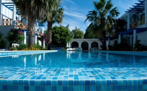 een zwembad met palmbomen en een gebouw bij Su Hotel - Bodrum in Bodrum City