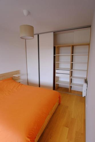 une chambre avec un lit orange et des murs blancs dans l'établissement T2 neuf haut standing Pornichet proche mer, à Pornichet