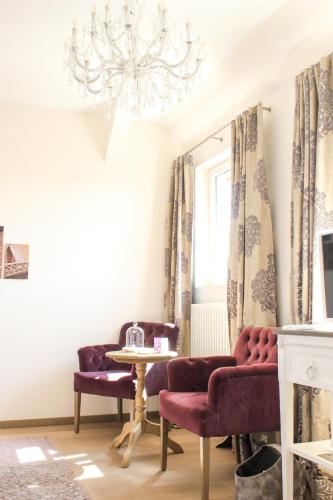 a room with two chairs and a table and a chandelier at Gästehaus im Weingut am Nil in Kallstadt