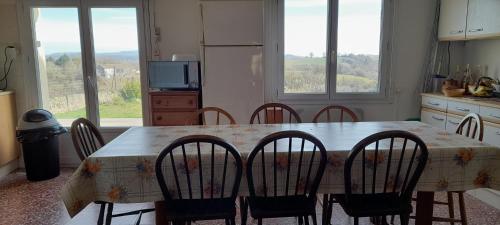 une cuisine avec une table avec des chaises et une table et une cuisine avec des fenêtres dans l'établissement Sympathique maison de village, à Les Rives