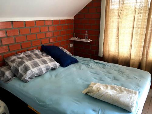 a blue bed with two pillows and a brick wall at Casa com piscina in Gravatá