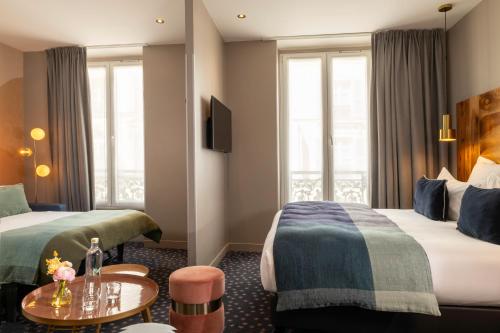 a hotel room with two beds and a table at Hôtel Maxim Folies in Paris