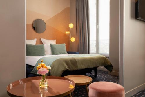 a hotel room with a bed and a table at Hôtel Maxim Folies in Paris