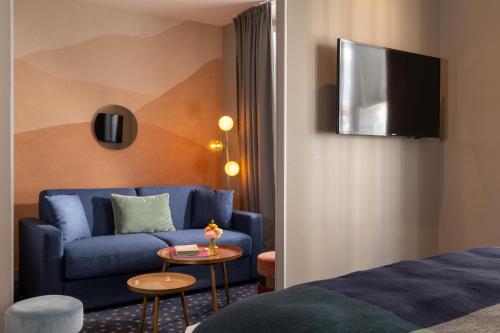 a hotel room with a blue couch and a table at Hôtel Maxim Folies in Paris