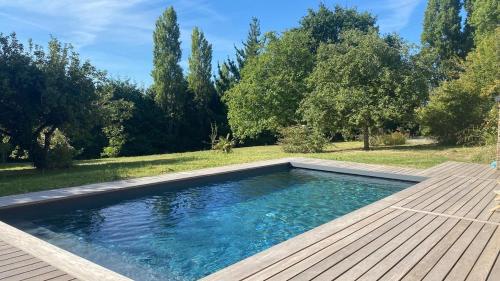 une piscine avec une terrasse en bois et des arbres dans l'établissement Grande Capitainerie en bord de Rance, à Plouër-sur-Rance
