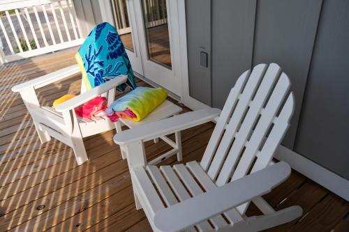 two white chairs sitting on a porch next to a door at Salty Shells - Spacious 3 Bedroom, 4 Bathroom Retreat in Orange Beach Just Steps from the Sand in Orange Beach