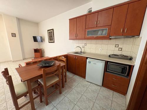 a kitchen with wooden cabinets and a table and a sink at Delta Apartments in Pherrai