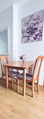 a wooden dining room table and chairs with a vase on it at Willa Ada Pokoje & Apartamenty in Karwia