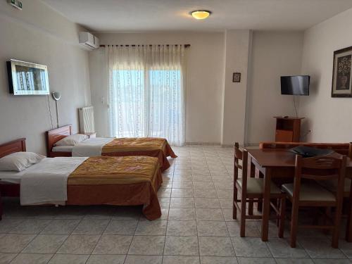 a hotel room with two beds and a table and a desk at Delta Apartments in Pherrai
