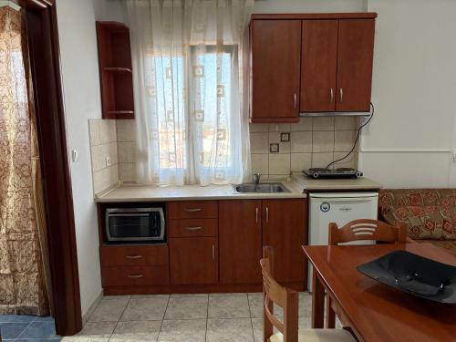 a kitchen with wooden cabinets and a sink and a table at Delta Apartments in Pherrai