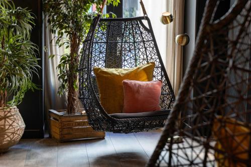 a hammock with pillows in a room with potted plants at Hôtel Maxim Folies in Paris